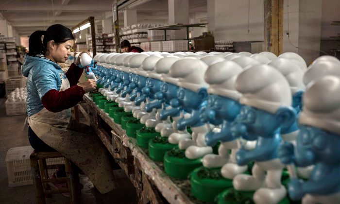 Un'operaia dipinge dei Puffi di ceramica in una fabbrica di nella Provincia cinese del Fujian. (Kevin Frayer/Getty Images) 