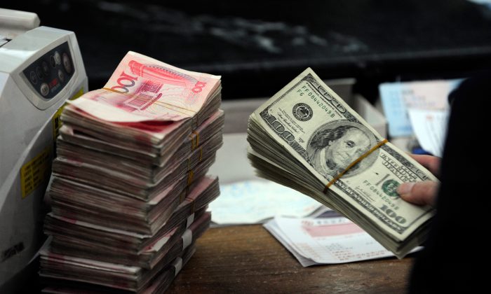 Un impiegato di una banca cinese si prepara a contare una pila di dollari americane insieme a un'altra pila di yuan in una banca a Hefei. Da quando miliardi di dollari stanno uscendo dalla Cina e minacciando le sue riserve in valuta estera, il Governo ha iniziato un giro di vite ai piccoli negozi finanziari, nella speranza di arginare il fenomeno. (STR/AFP/Getty Images) 