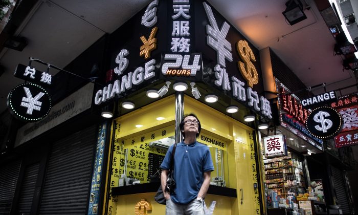 Un uomo presso una cabina di cambio di valuta estera a Hong Kong, il 13 agosto, 2015. La svalutazione dello yuan potrebbe comportare effetti sul prezzo delle materie prime, sulle vendite al dettaglio delle multinazionali in Cina e una possibile guerra valutaria in Asia. (Philippe Lopez/AFP/Getty Images) 