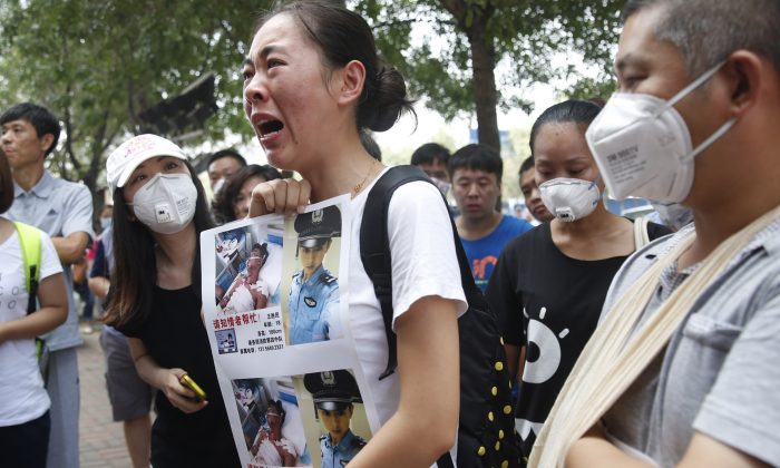 Un membro della famiglia (C) di un vigile del fuoco disperso in seguito alle recenti esplosioni in un deposito chimico di Tianjin, mentre protesta all'esterno di un hotel dove le autorità tengono una conferenza stampa, il 16 agosto 2015. Il bilancio ufficiale dei decessi è salito a 112 persone. (STR/AFP/Getty Images)