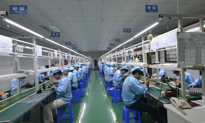 Operai cinesi assemblano un'alternativa a un orologio Apple in una fabbrica nello Shenzhen, il 22 aprile 2015. I dati pubblicati da un sito cinese, mostrano un quadro di recessione economica (STR/AFP/Getty Images) 