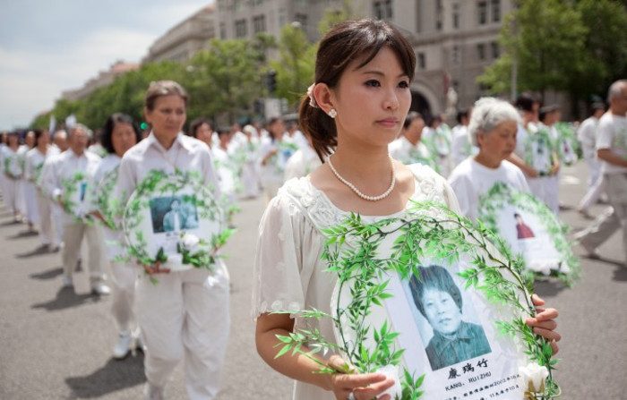 Alcuni praticanti del Falun Gong con in mano le foto delle vittime della persecuzione durante una parata a Washington, il 18 luglio 2011. Alcuni documenti rilasciati nel 2015 dalla autorità centrali cinesi, dimostrano che la persecuzione del Falun Gong viene ancora attuata come una politica ufficiale in Cina. (Epoch Times)