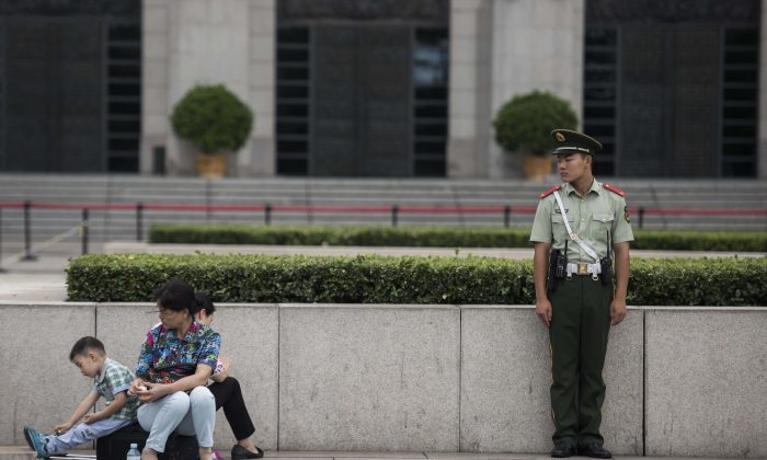 Una guardia paramilitare cinese guarda una famiglia in piazza Tiananmen a Pechino, l'1 settembre 2015. (Fred Dufour/AFP/Getty Images) 