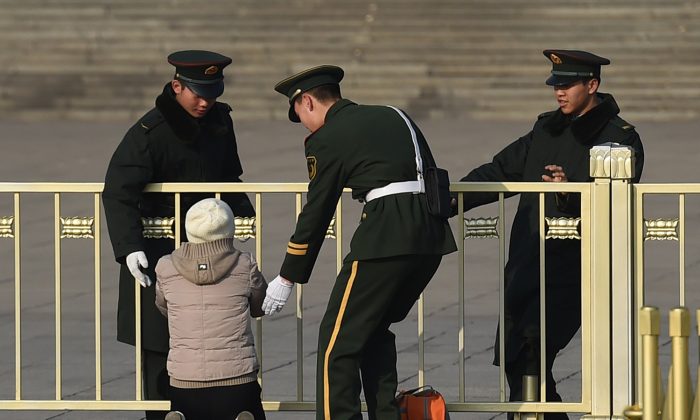 Gli agenti di polizia paramilitare fermano una donna che protesta in ginocchio di fronte alla Grande Sala del Popolo di Pechino, il 13 marzo 2015. (Greg Baker/AFP/Getty Images)