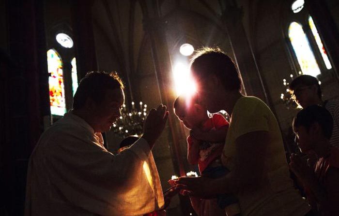 Una cattolica cinese fa la comunione durante una messa per l’Assunzione della Vergine Maria in una chiesa sanzionata dal governo, il 15 agosto 2014 a Pechino. (Kevin Frayer/Getty Images)