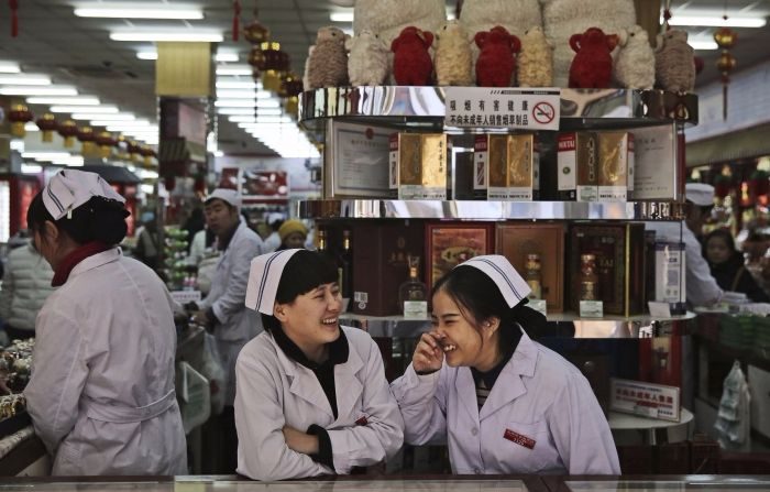 Impiegate cinesi parlano tra loro in un negozio a Pechino mentre attendono i clienti. 19 gennaio 2016. (Kevin Frayer/Getty Images)