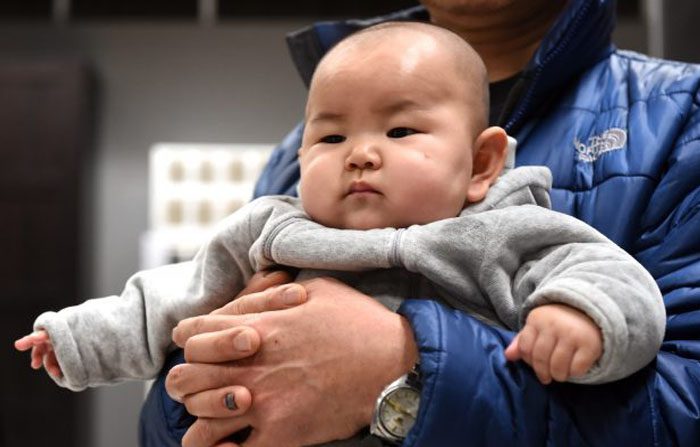 Un bambino cinese nelle braccia di suo padre in un negozio di mobili a Pechino il 19 gennaio 2015. (Goh Chai Hin / AFP / Getty Images)