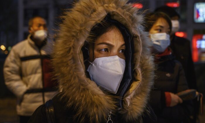 Impiegati cinesi indossano mascherine protettive mentre attendono l'autobus dopo aver lasciato il lavoro, Pechino, 2 marzo 2020. (Kevin Frayer / Getty Images)