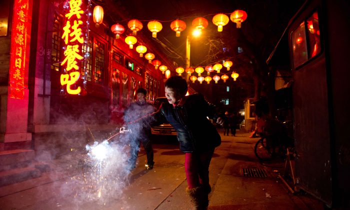 Una ragazza tiene in mano un petardo in un vicolo a Pechino durante il Festival delle Lanterne, che segna la fine dei festeggiamenti per il periodo del capodanno cinese. (Ed Jones / AFP / Getty Images)