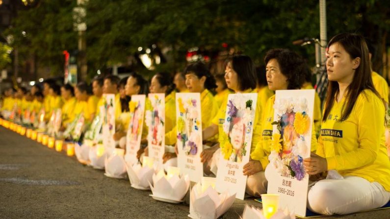 Praticanti del Falun Gong tengono una veglia a lume di candela davanti al consolato cinese di Toronto, il 13 luglio 2019, tra le braccia hanno le foto di praticanti morti a causa della persecuzione in Cina. (Handout)