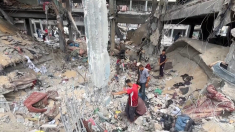 Palestinesi sfollati cercano tra le macerie di una scuola distrutta