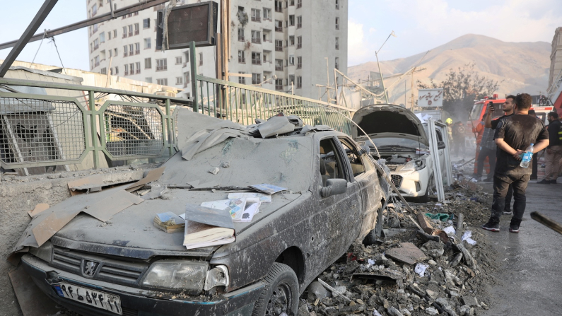 Persone attorno a veicoli danneggiati dopo gli attacchi israeliani, Teheran, 13 giugno 2025 (foto Majid Asgaripour/WANA West Asia News Agency via REUTERS).