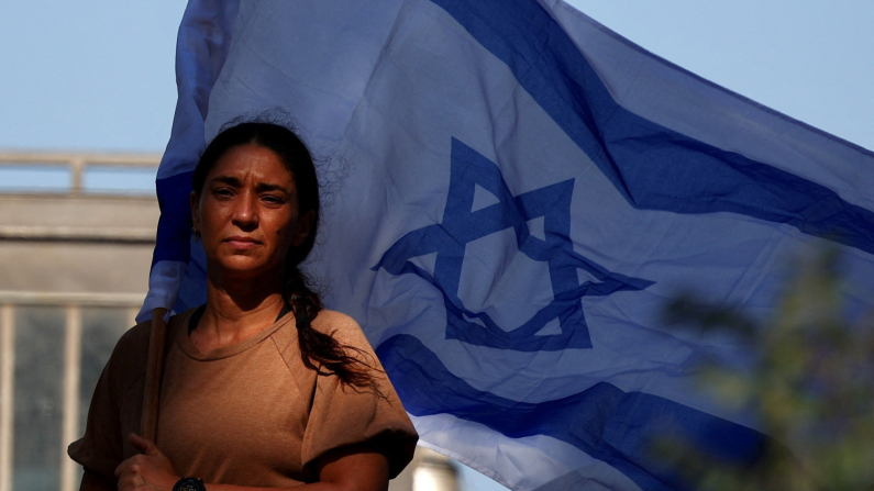 Una donna con una bandiera israeliana, prima del funerale del soldato israeliano sergente Maayan Baruch Pearlstein, ucciso durante il conflitto in corso a Gaza tra Israele e Hamas, a Misgav, Israele, 25 giugno 2025. REUTERS/Florion Goga