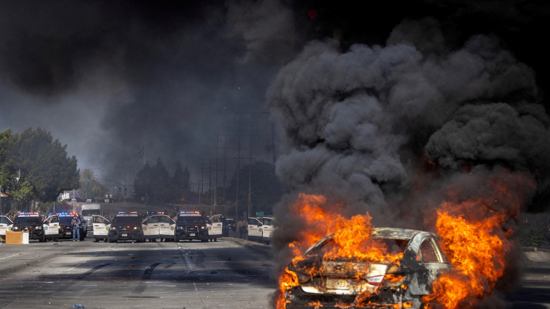 Un'auto brucia su Atlantic Boulevard durante uno scontro tra manifestanti e forze dell'ordine a Paramount City, nella contea di Los Angeles, 7 giugno 2025 (foto REUTERS/Barbara Davidson)