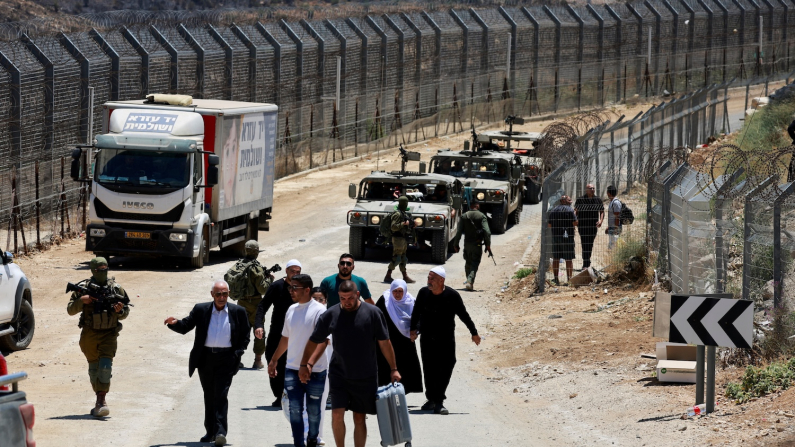 Cittadini siriani scortati dall'esercito israeliano mentre camminano da Majdal Shams verso la Siria, lungo la linea di cessate il fuoco tra le Alture del Golan occupate da Israele e la Siria, durante il conflitto in corso nelle aree druse in Siria, a Majdal Shams, 17 luglio 2025 (foto REUTERS/Ammar Awad).